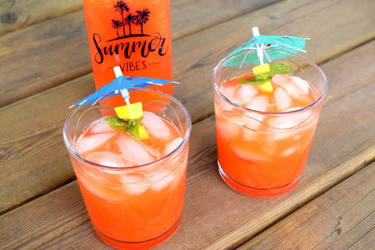 Summer mango pomegranate soda in glasses with umbrellas.