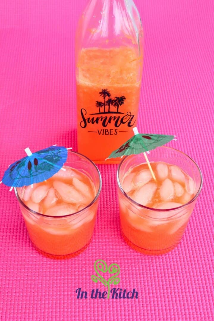 Summer mango pomegranate soda in glasses on pink background.