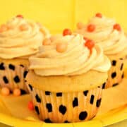 Moist, frosted pumpkin cupcakes on yellow plate.