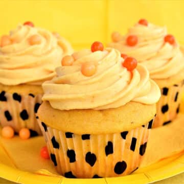 Moist, frosted pumpkin cupcakes on yellow plate.