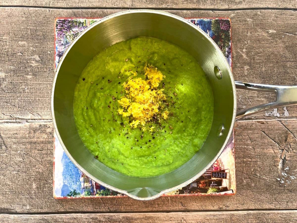 Pea purée in saucepan with lemon zest, salt and pepper.
