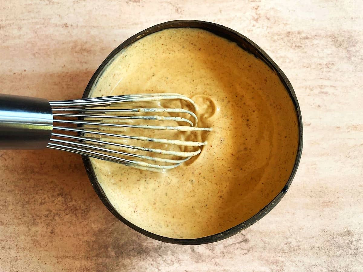 Taco pasta salad sauce in bowl with whisk.