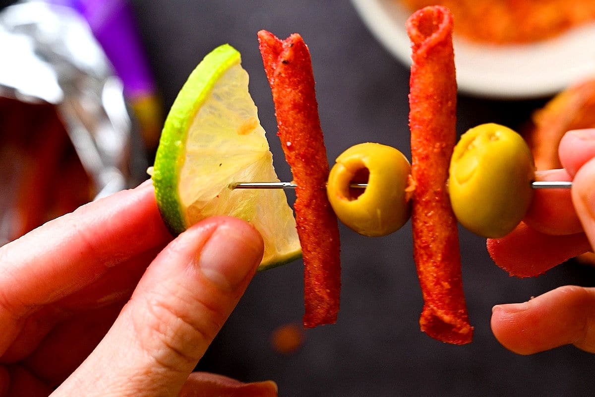 Caesar cocktail garnish with lime, Takis and olives.