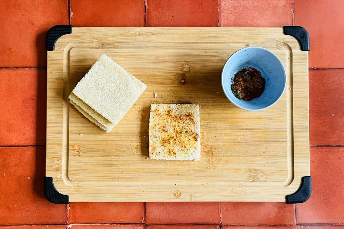 Slices of bread on cutting board with spices.