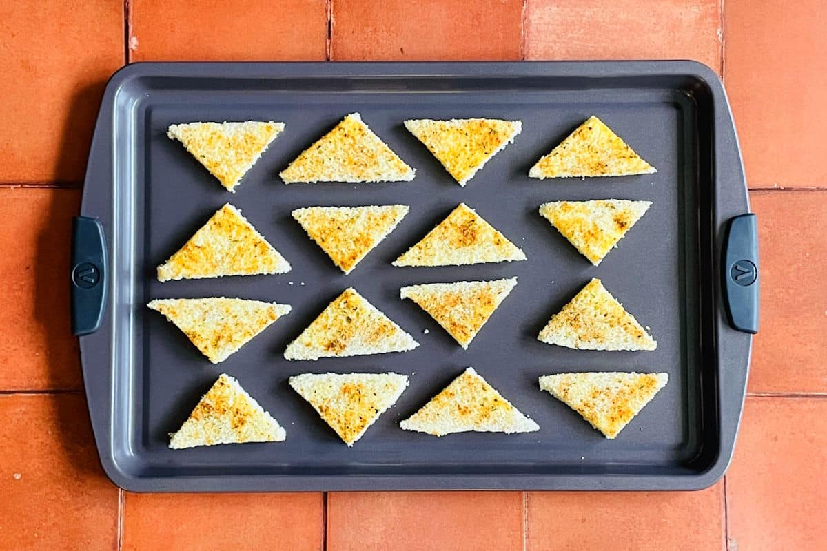 Toast triangles with spices on baking sheet.