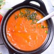 Tomato gravy in cast iron bowl with spoon.