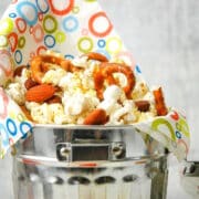 Popcorn snack mix in metal bucket with colorful napkin.