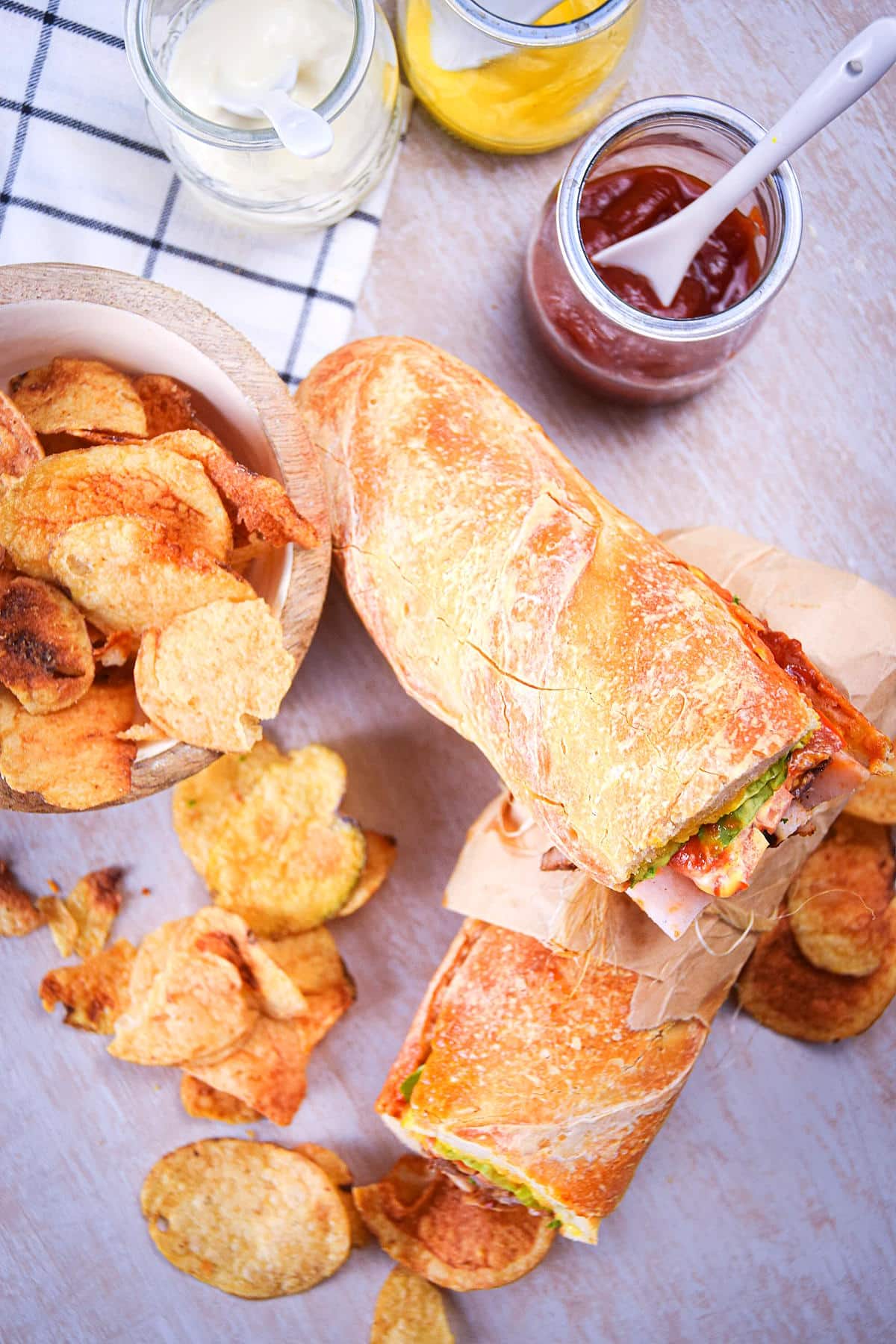 Tripleta sandwiches with chips and condiments on the side.