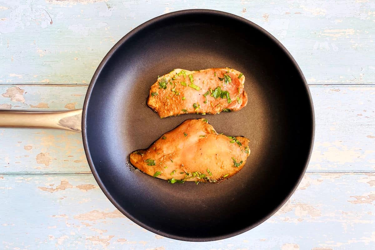 Pork and chicken in frying pan.