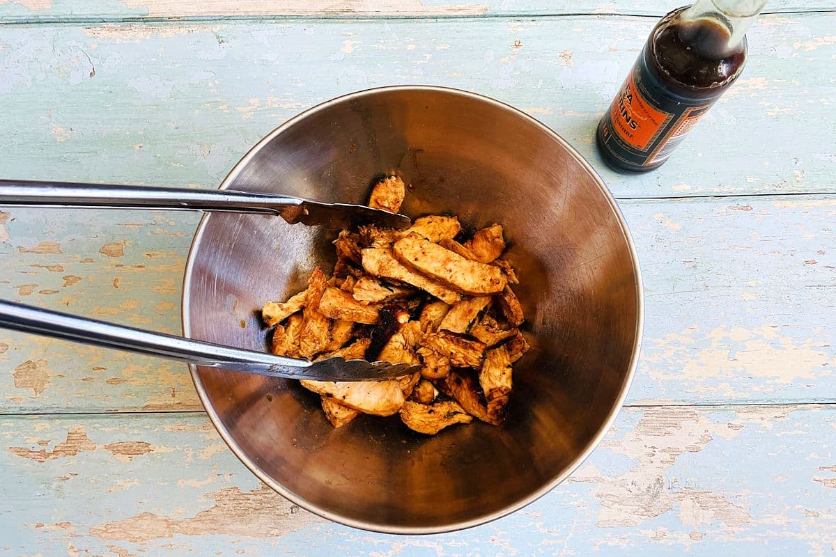 Cooked pork and chicken pieces in bowl with worcestershire sauce.