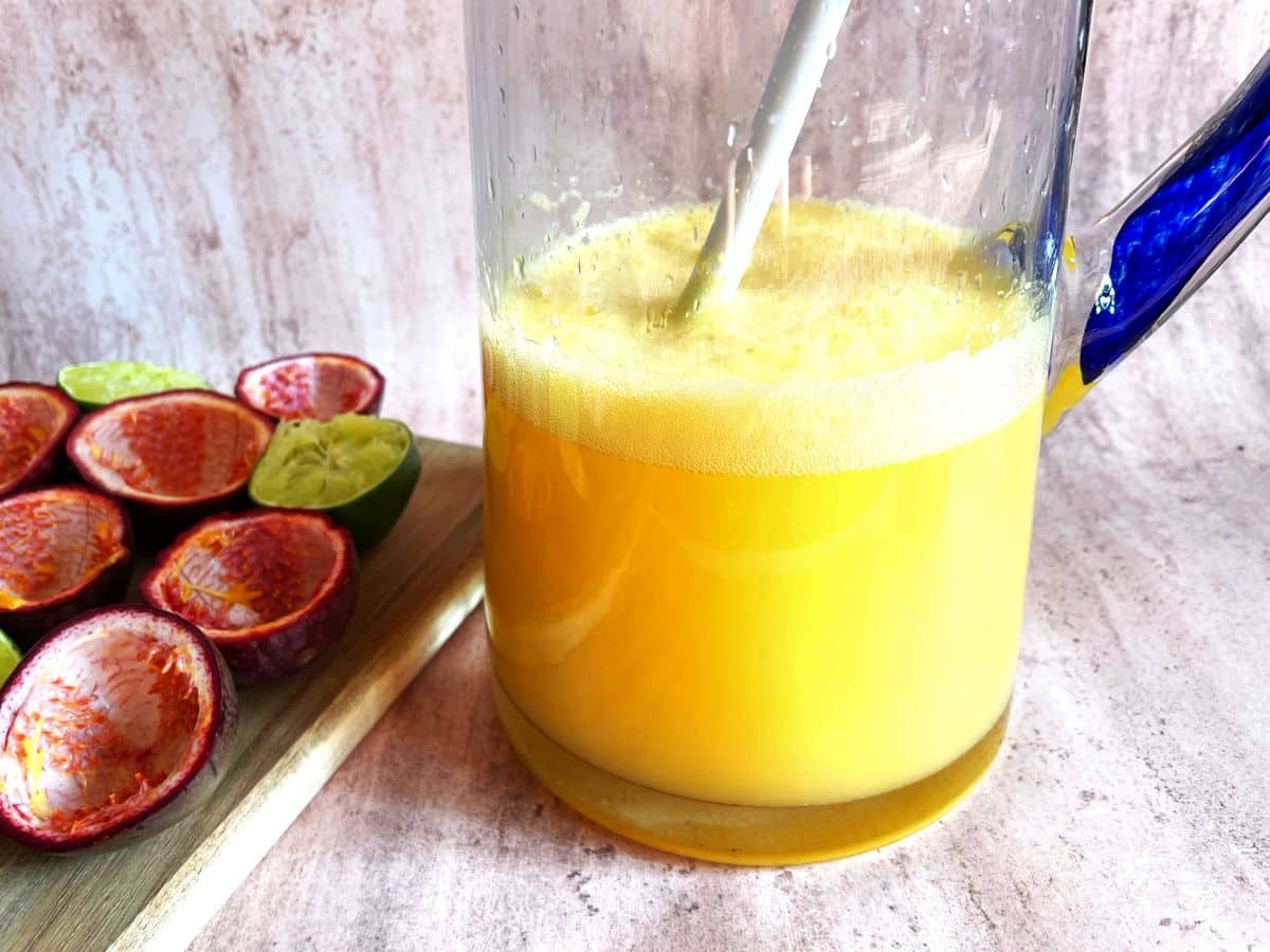 Passion fruit mojitos in glass pitcher with mixing spoon.