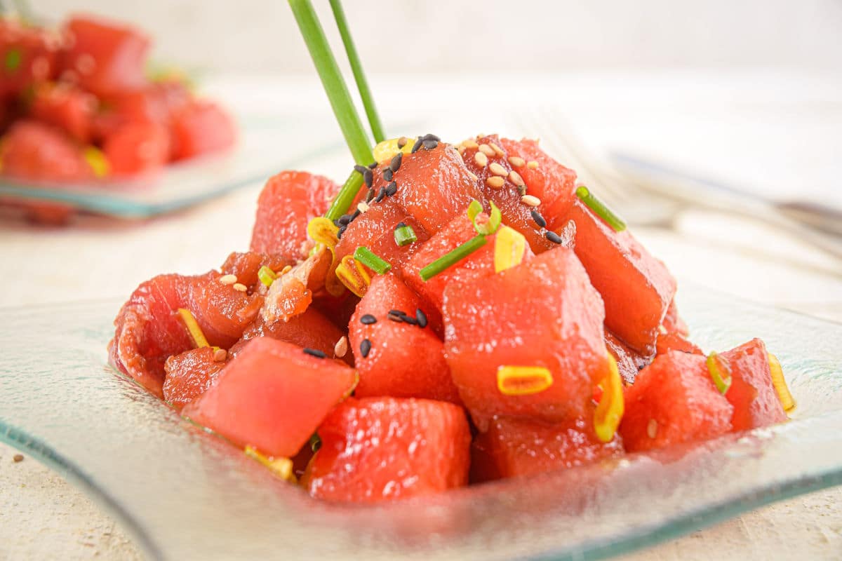 Tuna watermelon tartare on clear glass plate with chives.