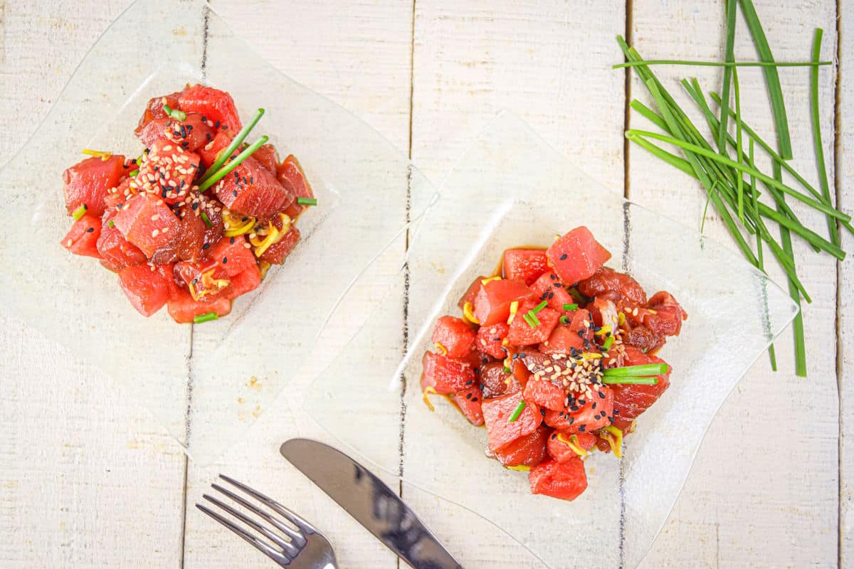 Tuna watermelon tartare on clear glass plates with chives on the side.