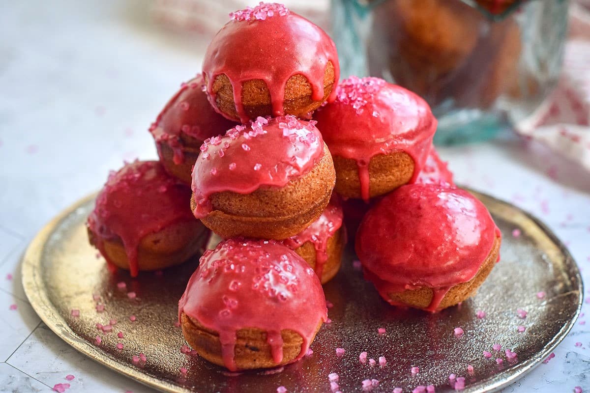 Valentine's day cake balls with pink frosting and sprinkles on plate.