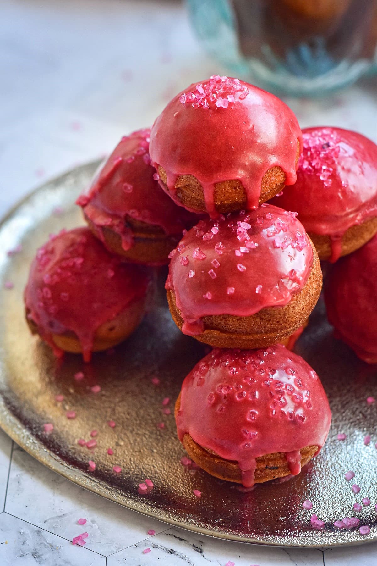 Valentine's day cake balls with pink frosting and sprinkles stacked on plate.