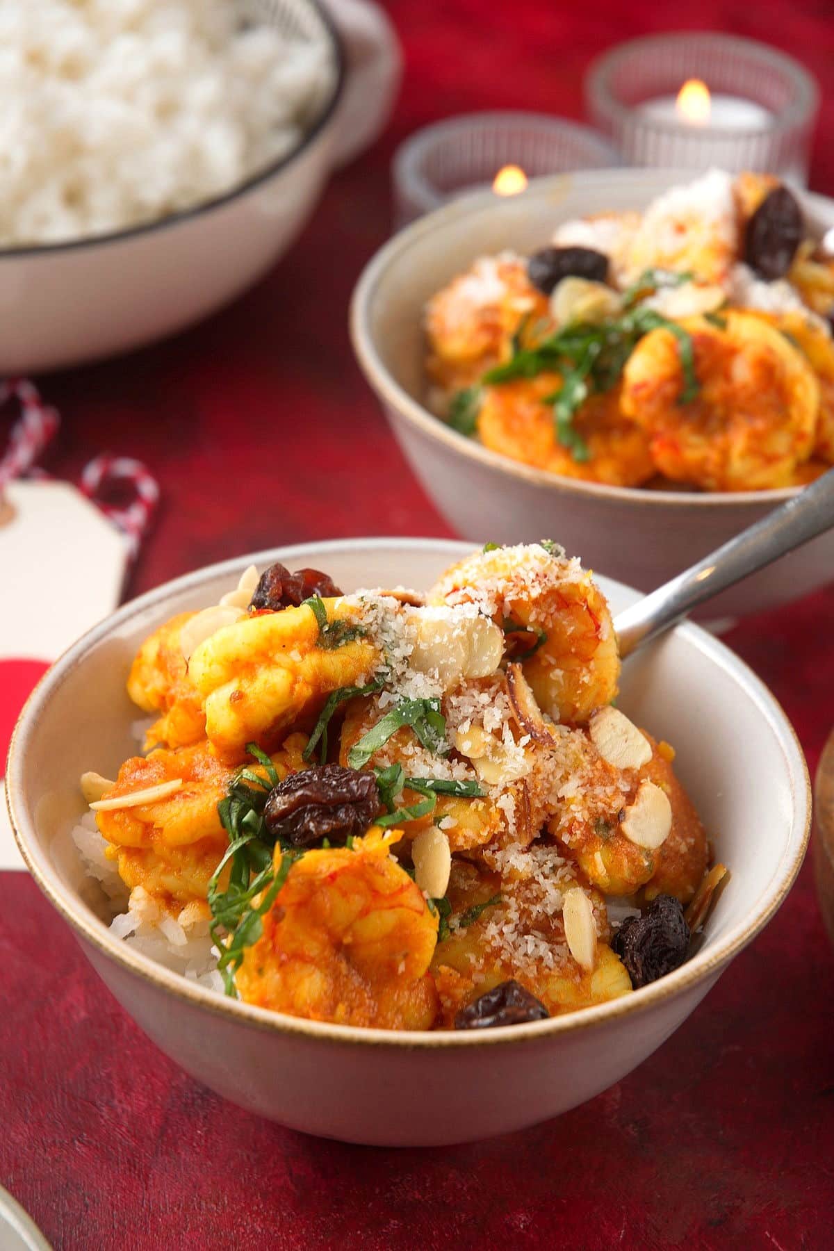 Shrimp curry in two bowls on deep red backround.
