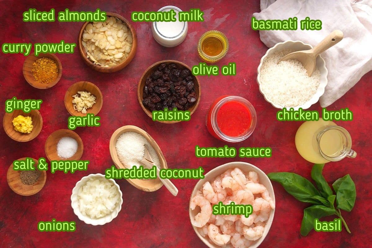 Shrimp curry ingredients prepped on deep red background.