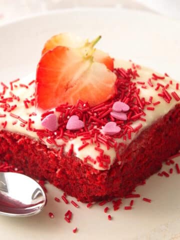 Valentine's Day cake slice on white plate with fresh strawberry slices.