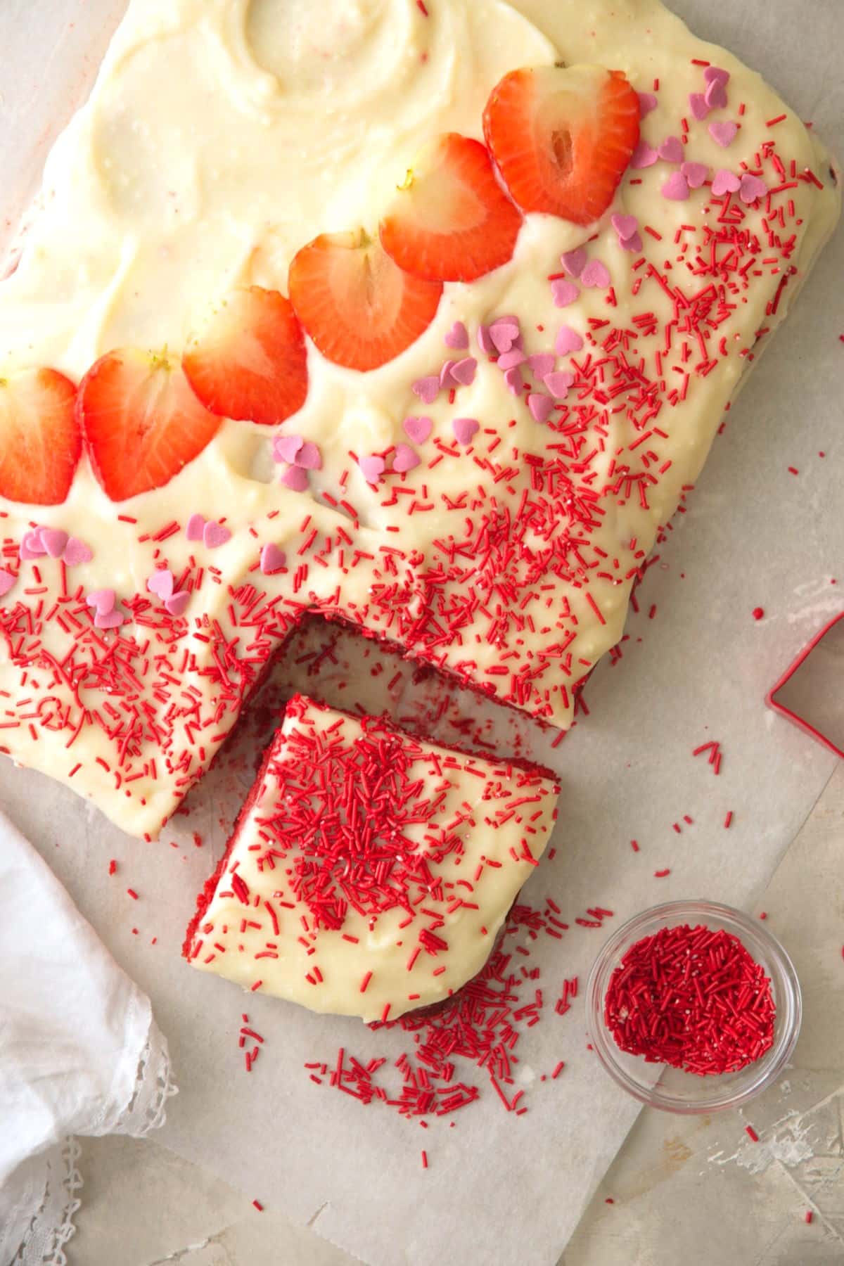 Frosted Valentine's Day sheet cake with strawberries and candy decorations.