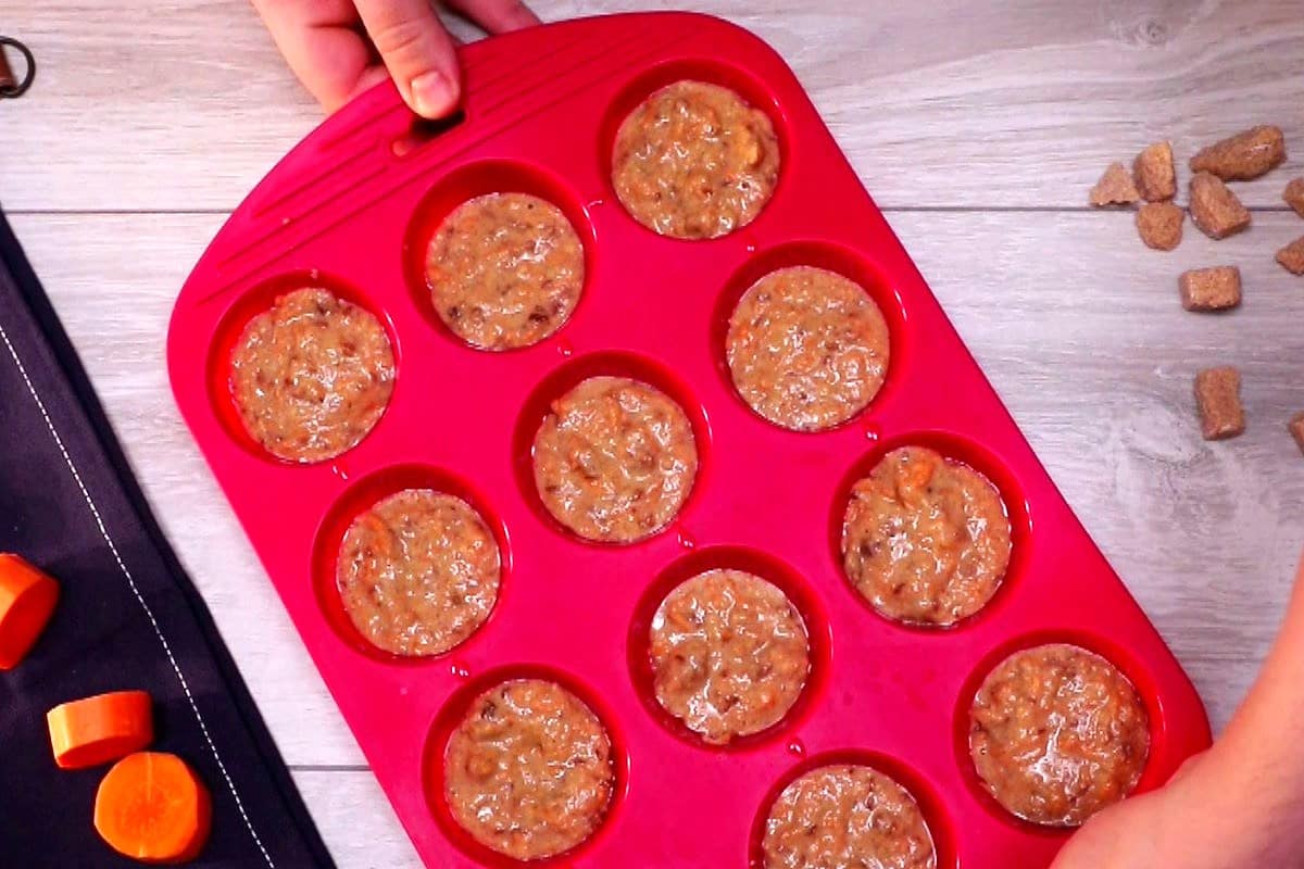 Carrot cupcake batter in red silicone muffin mold.