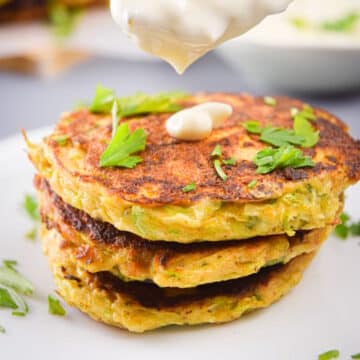 Vegetarian zucchini crab cakes stacked with a dollop of tartar sauce.