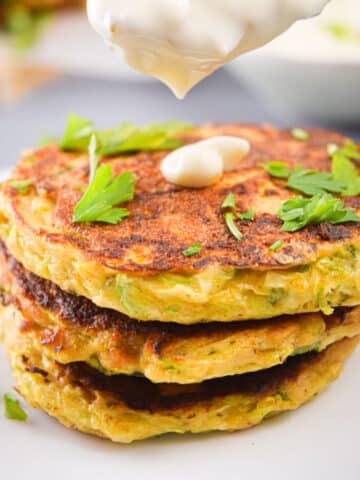 Vegetarian zucchini crab cakes stacked with a dollop of tartar sauce.