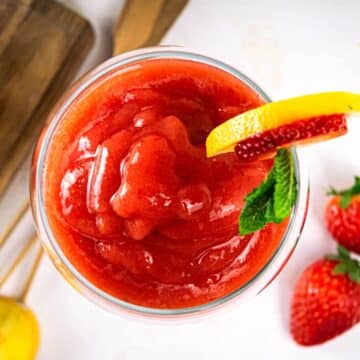 Virgin frozen strawberry daiquiri in wine glass with strawberry-mint garnish.