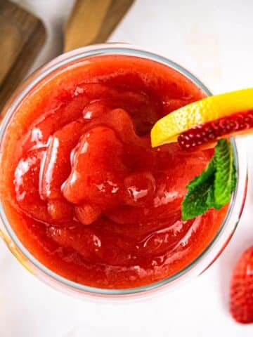 Virgin frozen strawberry daiquiri in wine glass with strawberry-mint garnish.