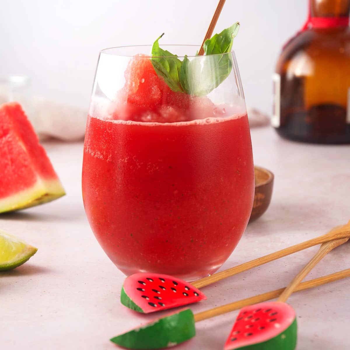 Watermelon basil cocktail in wine glass with watermelon swizzle stick.