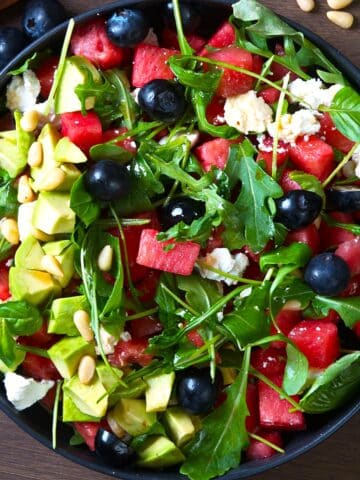 Watermelon salad with basil in black salad bowl.