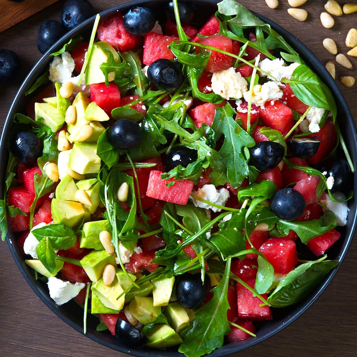 Watermelon salad with basil in black salad bowl.