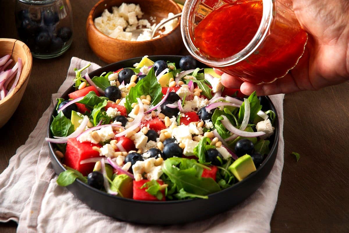 Watermelon basil salad in bowl with watermelon vinaigrette in jar.