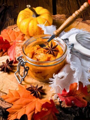 Pumpkin pie filling in jar with spoon and Autumn decorations.