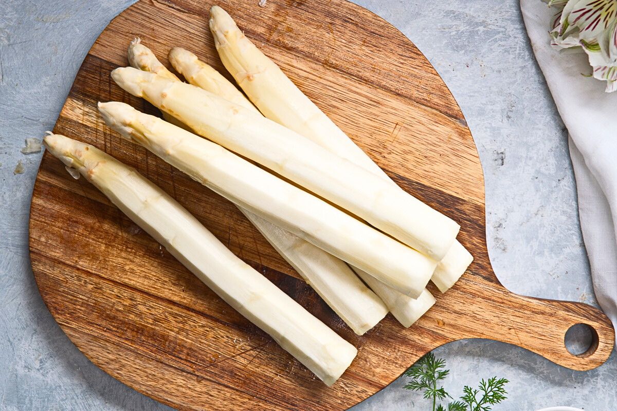 Peeled white asparagus on cutting board.