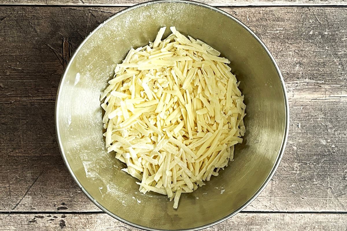 Shredded white cheddar cheese in bowl.